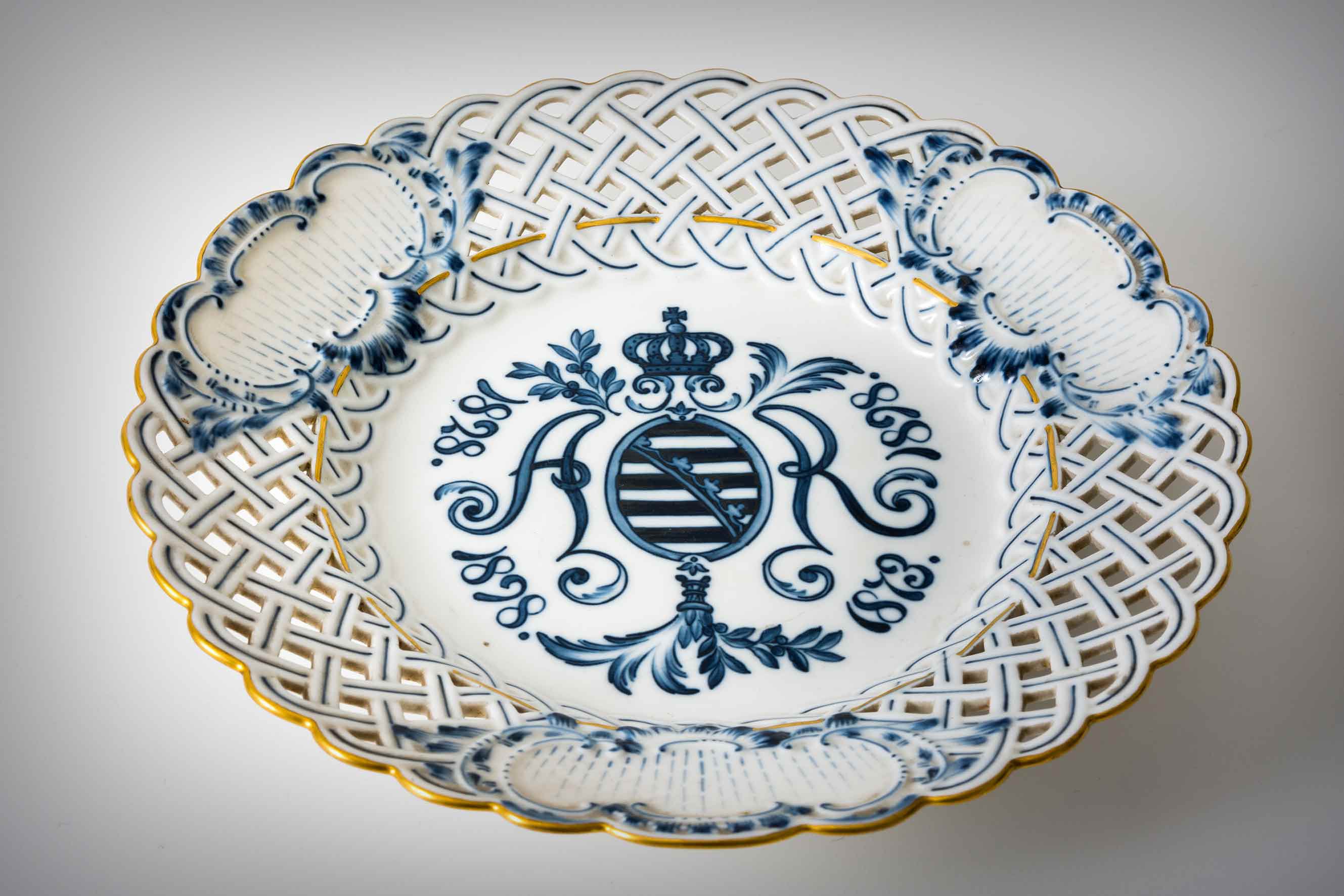 Zakladatele míšeňské manufaktury připomíná pamětní talíř z roku 1898. Písmena AR, Augustus Rex, která lemují saský znak završený vévodskou korunou, byla první značkou porcelánky.